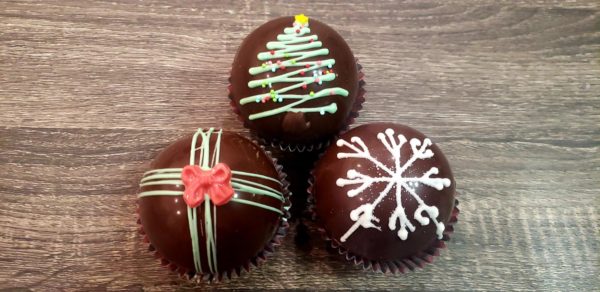 Hot cocoa bombs decorated for Christmas on top of a wood plank